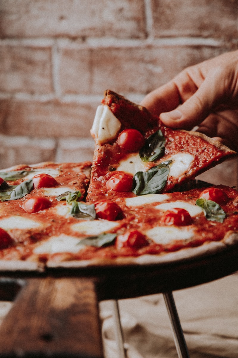 person holding sliced pizza with red sauce, Cauliflower Pizza Crust