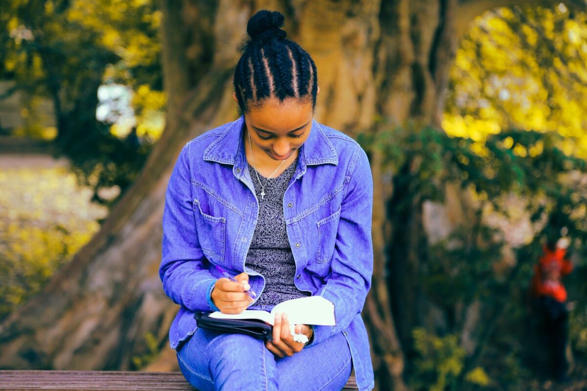 creative writing, selective focus photography of woman reading book while sitting at bench