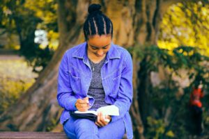 selective focus photography of woman reading book while sitting at bench