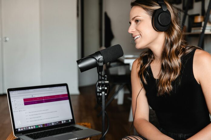 woman in black tank top sitting on chair in front of microphone, do a podcast