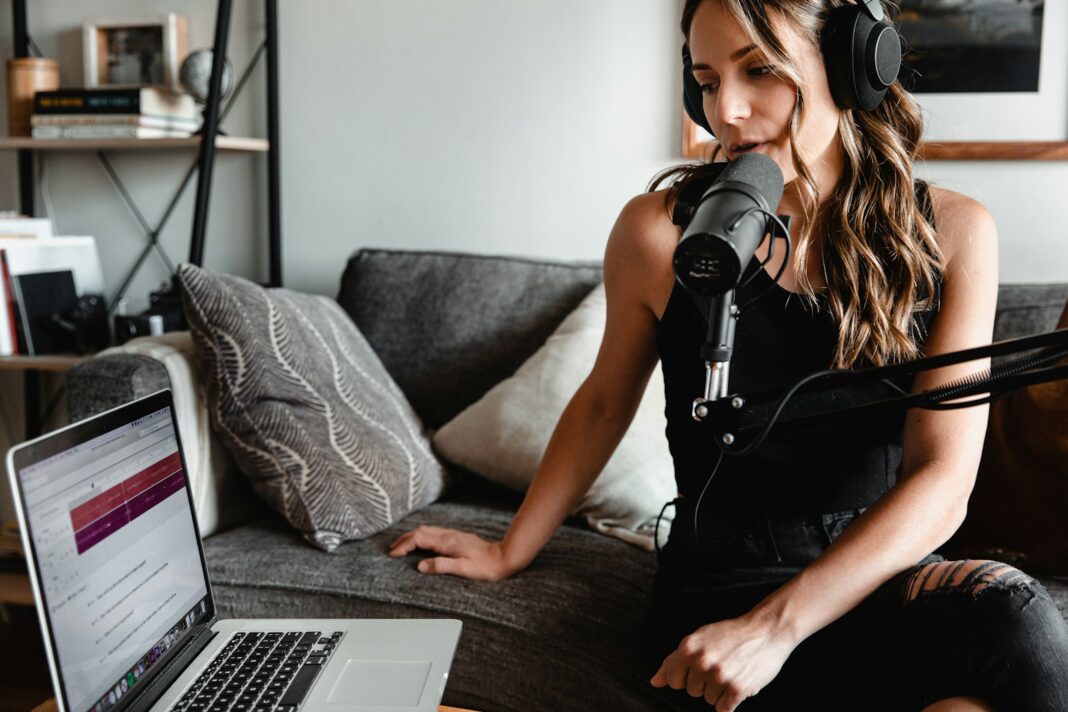 woman in black tank top sitting on couch using MacBook, podcast