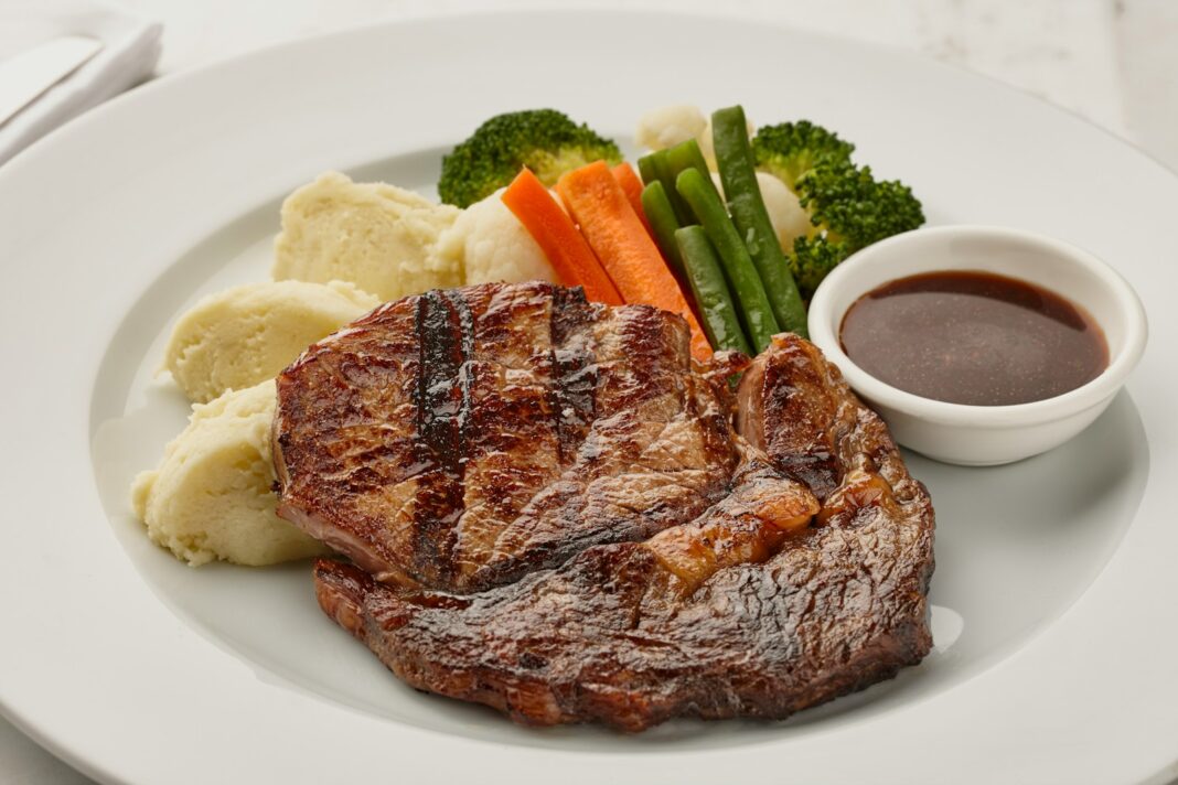 a white plate topped with meat and veggies, Pan Fried Pork Chops