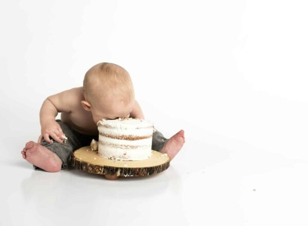 Binge eating kid sitting beside round cake close-up photography