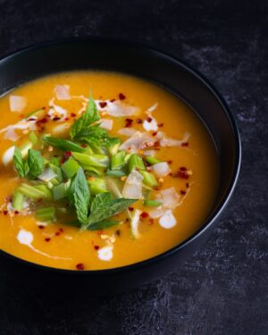 thai pumpkin soup soup with green leaf on black ceramic bowl