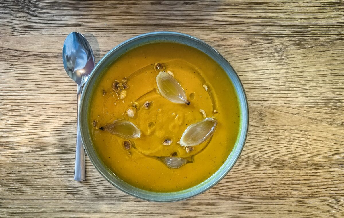 a bowl of pumpkin soup on a wooden table