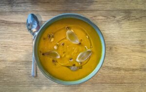 a bowl of pumpkin soup on a wooden table