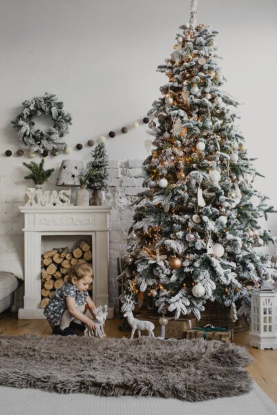 Charming indoor Christmas scene with a decorated tree and child by a cozy fireplace.