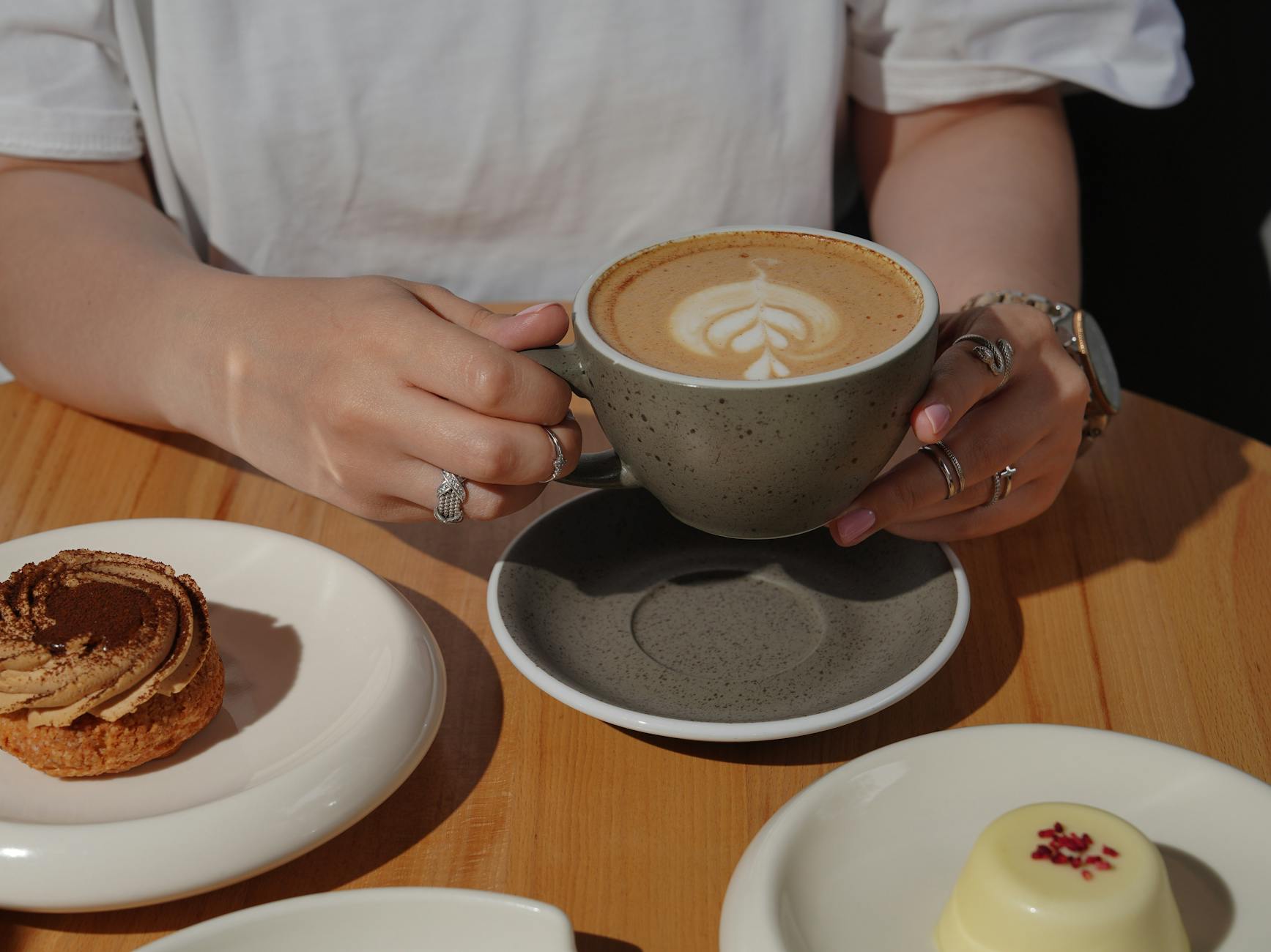 close up of a woman sitting at a table with a cup of cappuccino