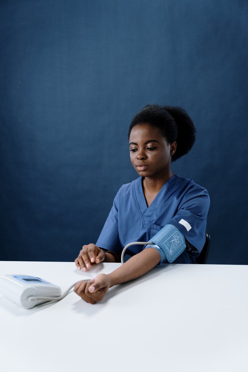 a healthcare worker measuring her own blood pressure using a sphygmomanometer
