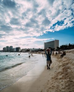 Vibrant seaside scene with people enjoying the beach under a cloudy sky.