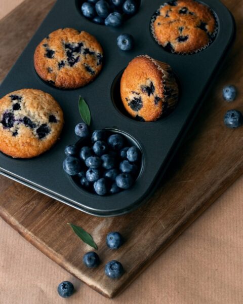 Blueberry muffins in a muffin tin on a cutting board