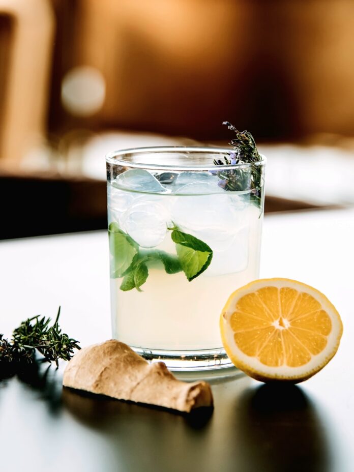 a glass with a drink and a lemon slice on a table
