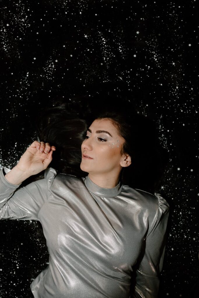 A captivating portrait of a woman in a silver shirt lying on a starry background, evoking a futuristic and cosmic vibe.