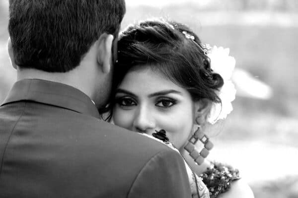 Personality Type You Attract - Close-up black and white portrait of a bride embracing her groom outdoors.