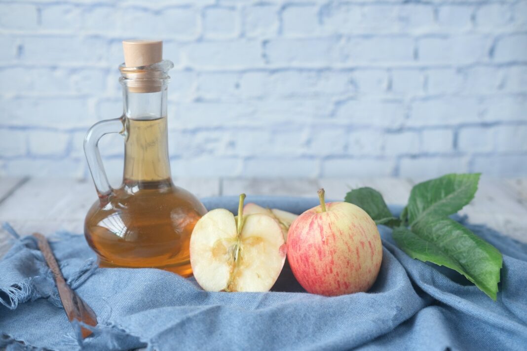 6 Benefits Drinking Apple Cider Vinegar - clear glass bottle with red liquid beside sliced lemon on blue textile