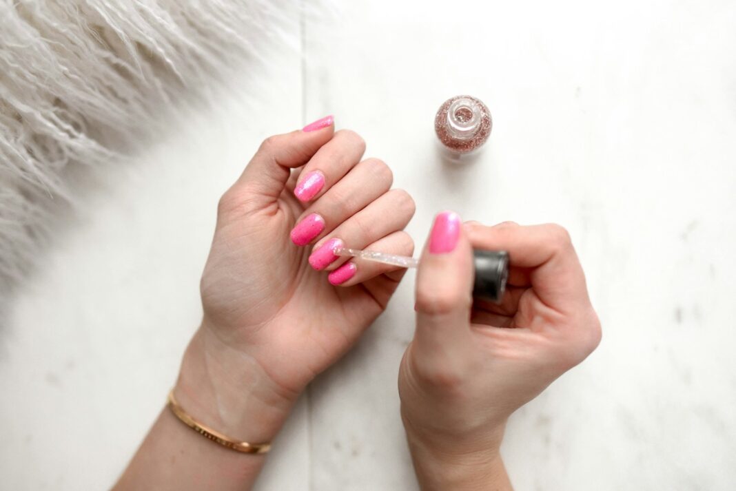 Gel Polish Banned - person spreading glittered nail polish on pink nails