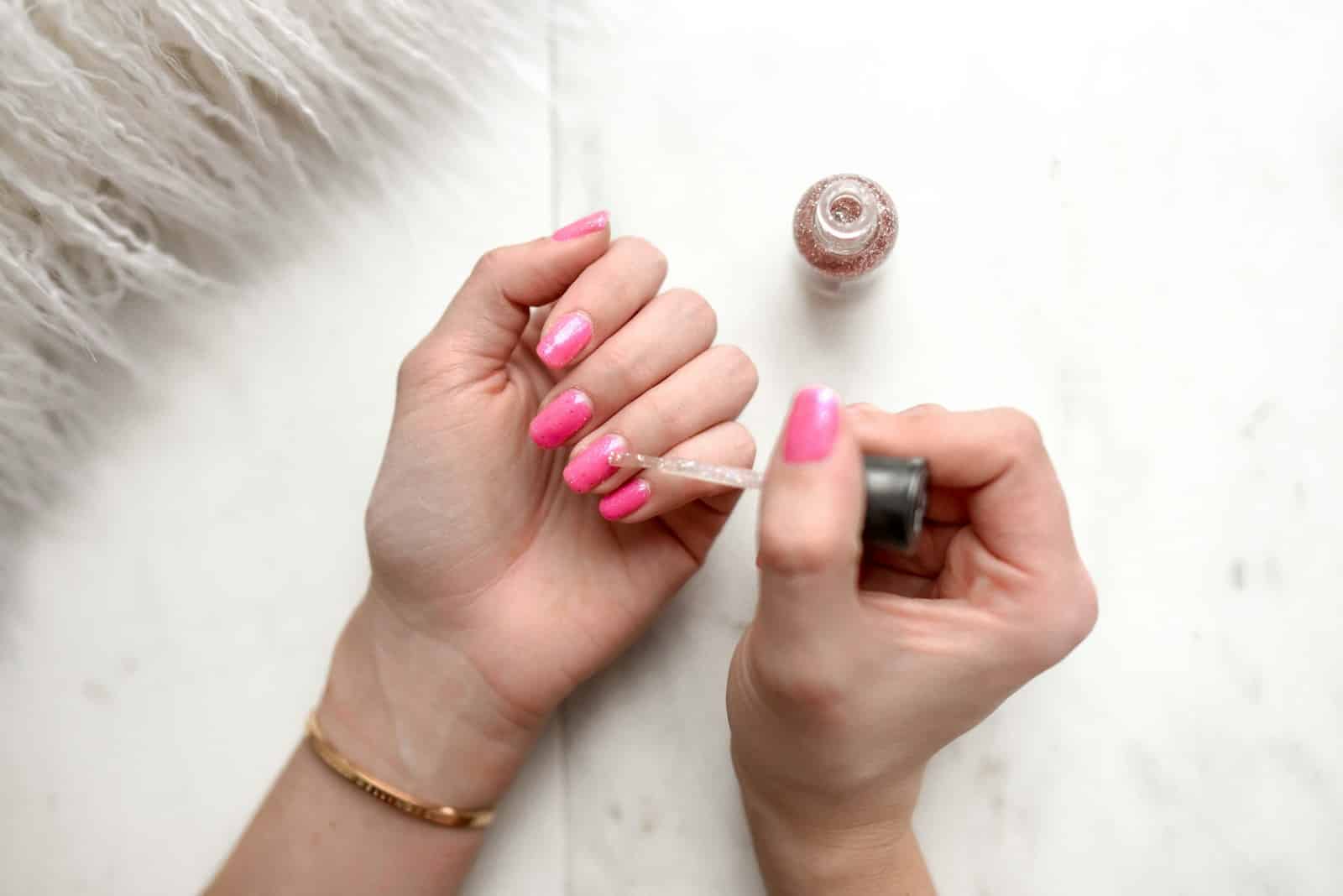 Gel Polish Banned - person spreading glittered nail polish on pink nails