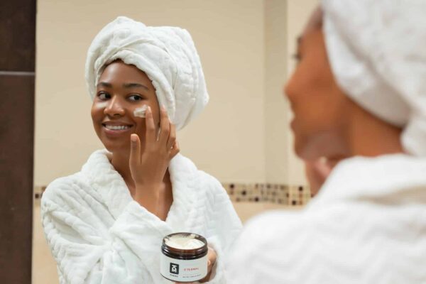 Skincare Routines - a woman with a towel on her head and a jar of cream on her face