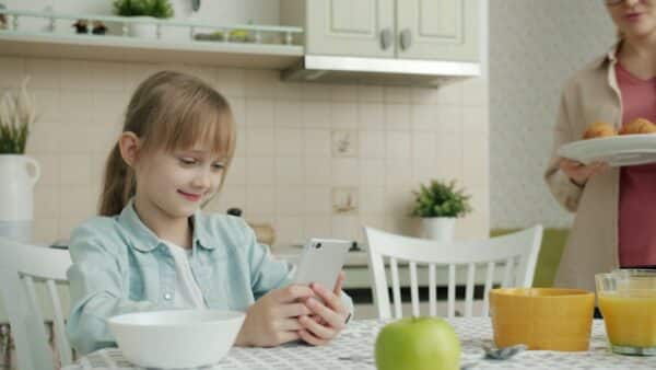 Smartphone - Girl using phone at kitchen table with breakfast