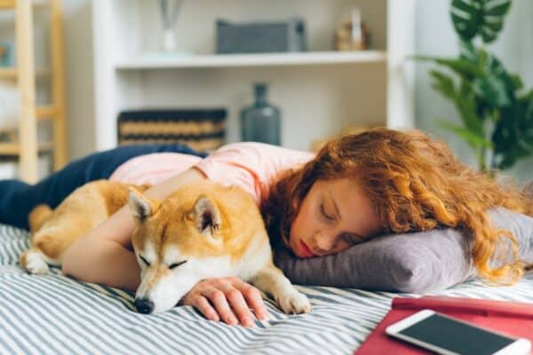 Better sleep - a woman laying on a bed next to a dog