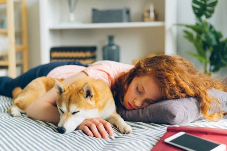 Better sleep - a woman laying on a bed next to a dog