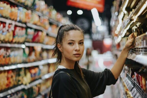 Grocery bill - woman selecting packed food on gondola