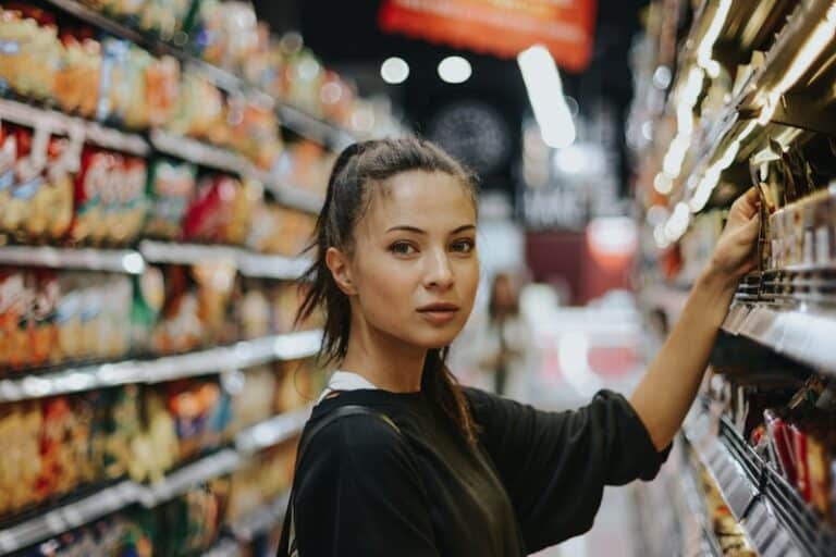 Grocery bill - woman selecting packed food on gondola