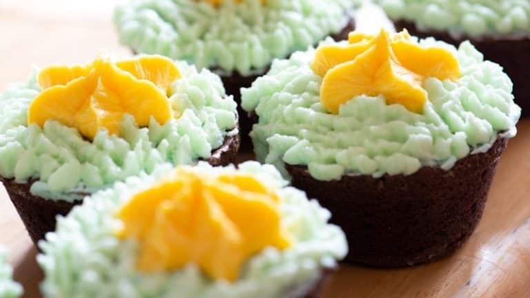 yellow and green cake with white icing on top