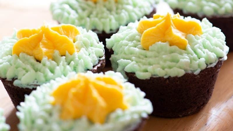 yellow and green cake with white icing on top