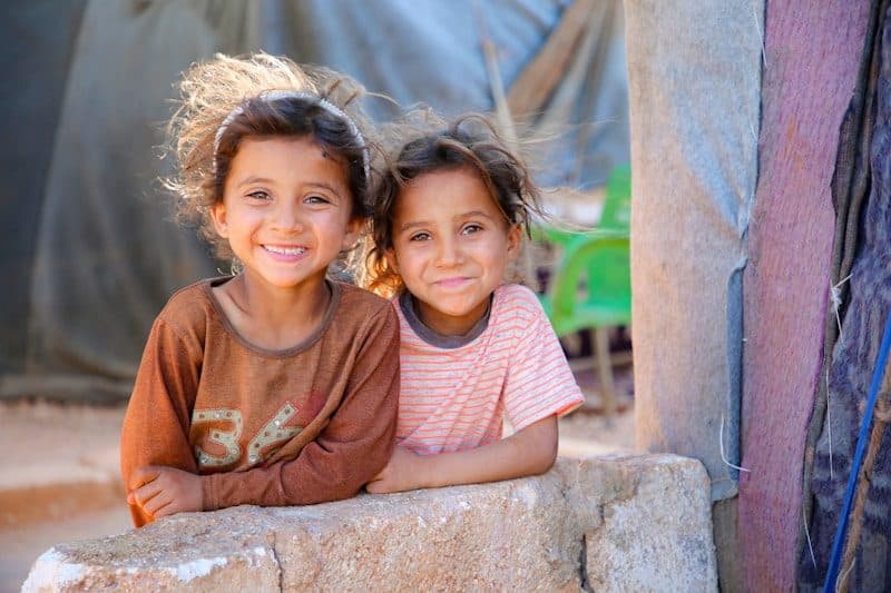 Two young children sitting on a stone wall