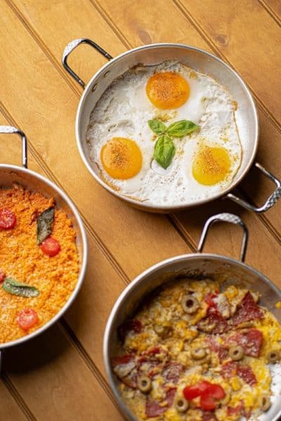 Three pans of breakfast food on wooden table