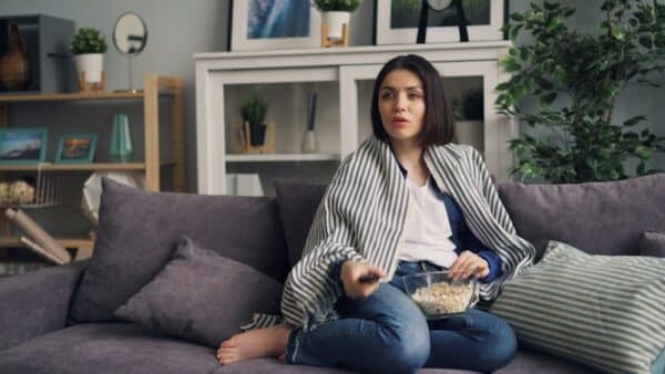 Binge-Watching a woman sitting on a couch eating popcorn