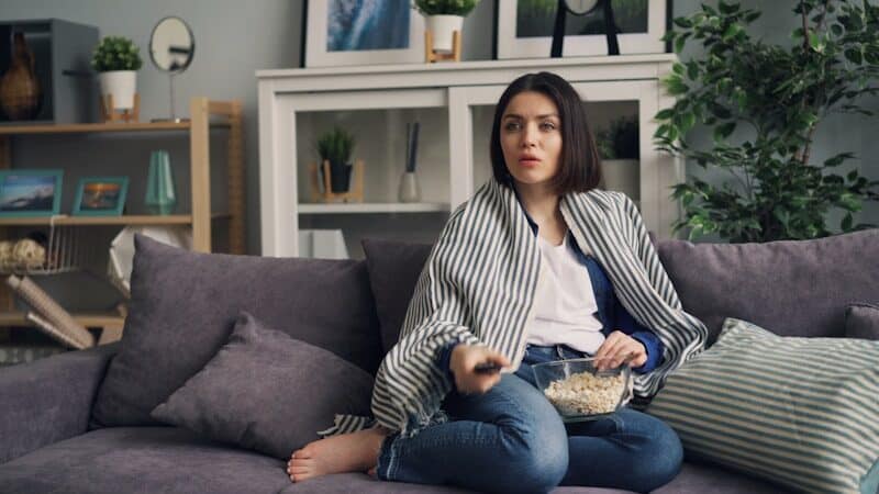 Binge-Watching a woman sitting on a couch eating popcorn