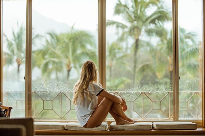 Wellness Overload: Are We Actually Healthier? - woman sitting on white cushion near glass window